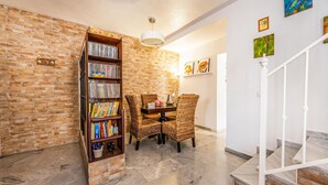 A room with a brick wall, a bookshelf, wicker chairs, a table, and a staircase. - 2 bedroom nice home in Aznalcázar (Aznalcázar)
