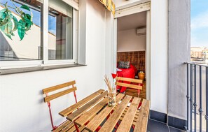 Eine hölzerne Bank und ein Tisch vor einem Gebäude mit Fenster, Tür und Blick auf die Straße.