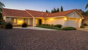 A two-story house with a red-tiled roof, a driveway, and a well-maintained front yard. - Private bedroom in Western Horizon Home (Hemet)