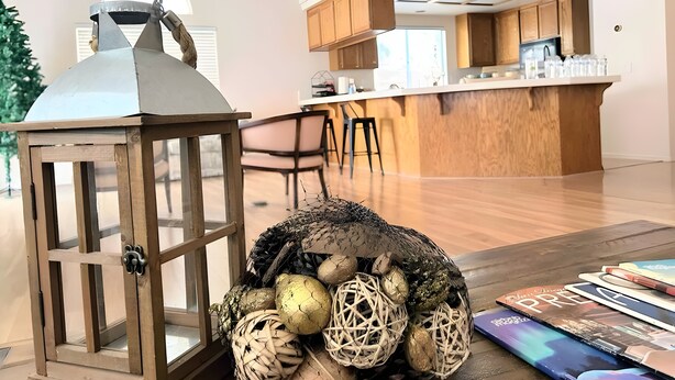 A modern kitchen with wooden cabinets, a central island, and a dining area with chairs. - Private bedroom in Western Horizon Home (Hemet)