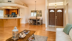 A spacious living area with a wooden floor, a dining table with chairs, a sofa, and a kitchen area with wooden cabinets and a microwave. - Private bedroom in Western Horizon Home (Hemet)