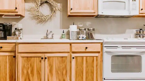A kitchen with wooden cabinets, a microwave, and a stove. - GrueneGusthaus#1| Private Condo +Golf Cart Rentals (New Braunfels)