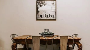 A dining table with four chairs, a framed picture on the wall, and a small decorative item on the table. - GrueneGusthaus#1| Private Condo +Golf Cart Rentals (New Braunfels)