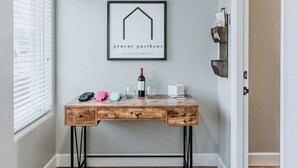 A wooden desk with a wine bottle, glasses, and a framed sign above it. - GrueneGusthaus#1| Private Condo +Golf Cart Rentals (New Braunfels)