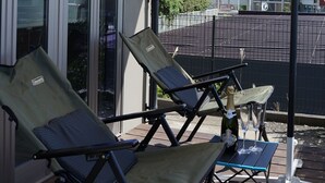 A balcony with two lounge chairs, a table with a bottle and glasses, and a large umbrella. - Yuigahama Chiyo (Kamakura)