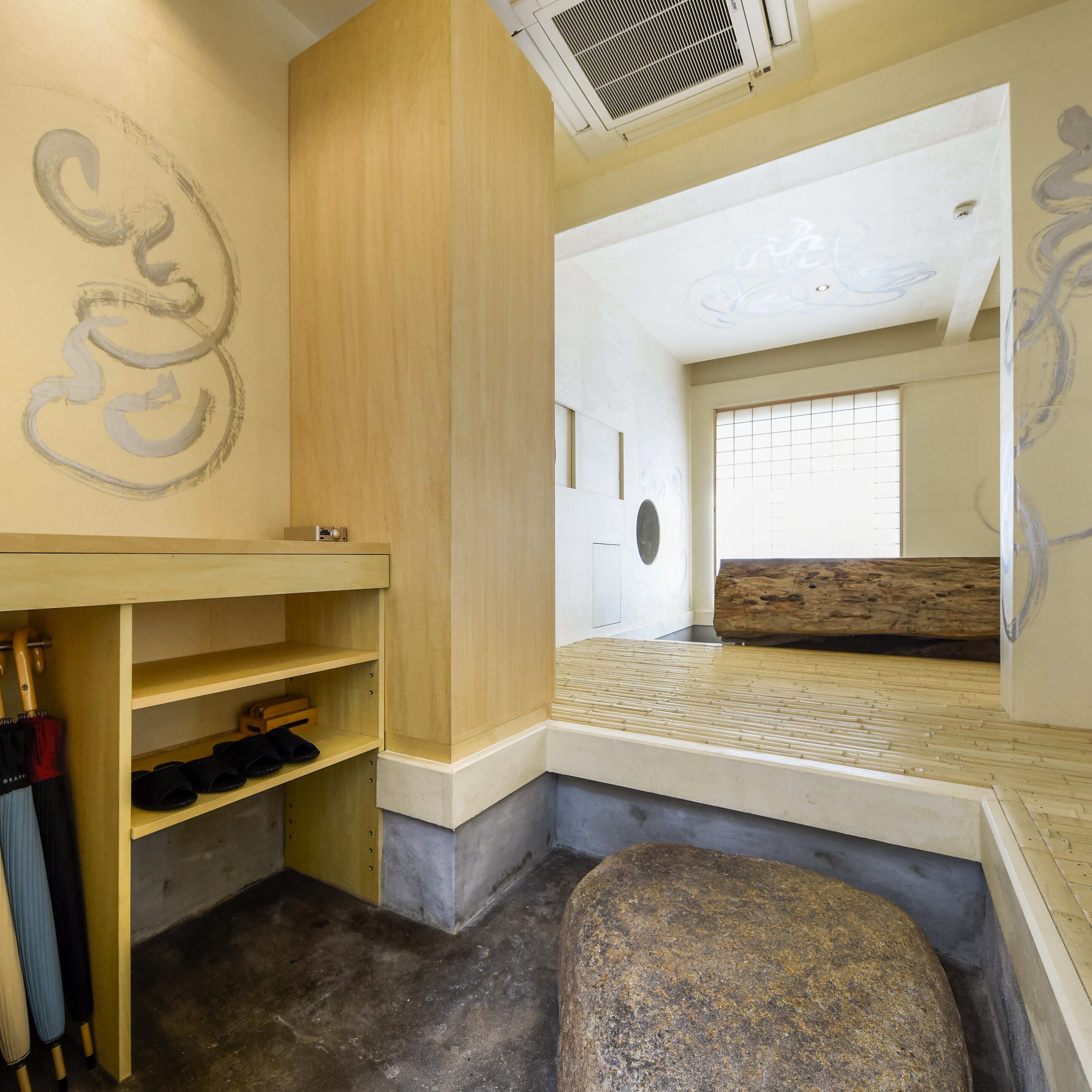 A room with a wooden desk, shelves, a large rock, and a view of a traditional Japanese room with tatami mats and a shoji screen.