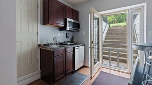 A kitchen with dark wood cabinets, a stainless steel microwave, and a dishwasher.