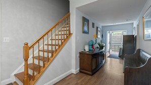 A staircase with wooden balusters, a dark wooden bench, and a door leading to an outdoor area.