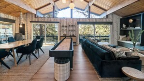A spacious room with a pool table, a dark blue sofa, and a wooden ceiling. - Ski View Chalet - Super Chic & Modern, Hot Tub, Shuffleboard, Views (Big Bear Lake)