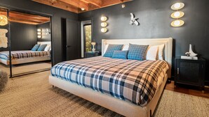 A bedroom with a large bed, a mirror, and a wall-mounted light fixture. - Ski View Chalet - Super Chic & Modern, Hot Tub, Shuffleboard, Views (Big Bear Lake)