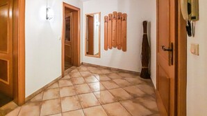 Un pasillo con suelo de baldosas, puertas de madera y un perchero en la pared.