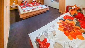 Una habitación de hotel con una cama, una mesita de noche pequeña y otra mesita auxiliar.