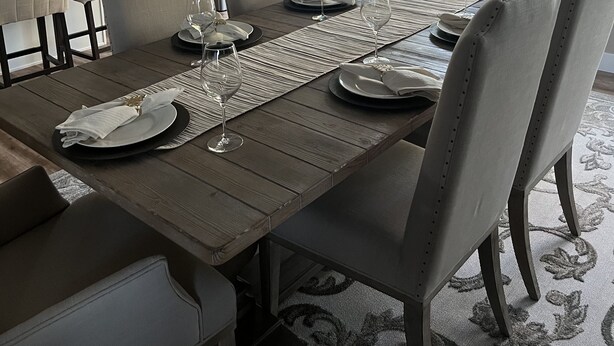 A dining area with a wooden table set for six, surrounded by six chairs. - Warm and inviting home centrally located. (La Quinta)