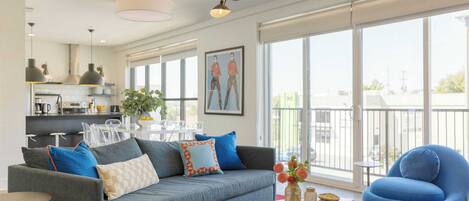 A modern living room with a grey sofa, blue armchair, and a coffee table with decorative items.