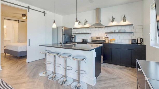 A modern kitchen with a central island, bar stools, and pendant lighting. - The Carter by AvantStay (Nashville)