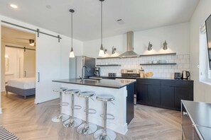 A modern kitchen with a central island, bar stools, and pendant lighting. - The Carter by AvantStay (Nashville)