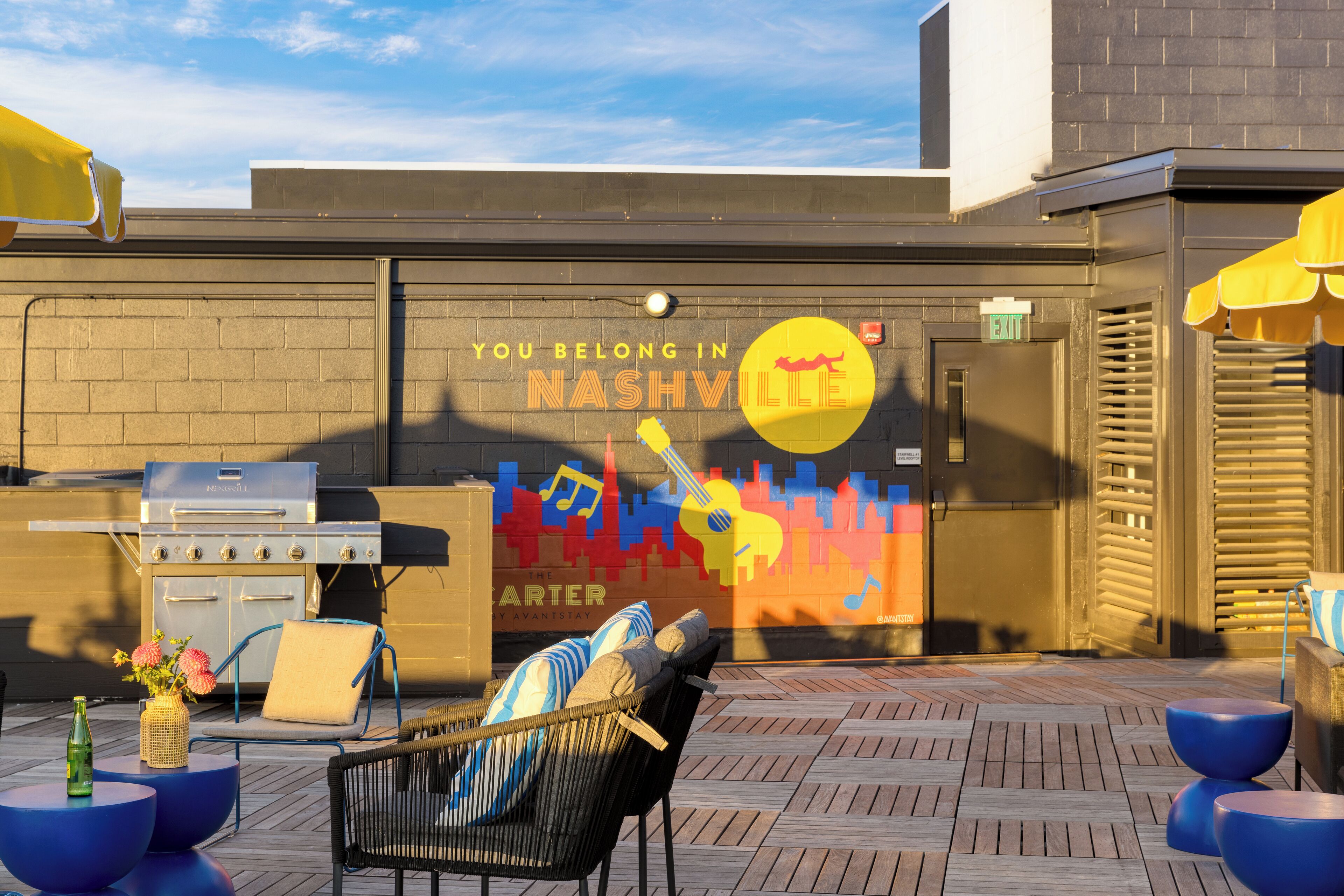 An outdoor patio with a grill, seating, and a mural.
