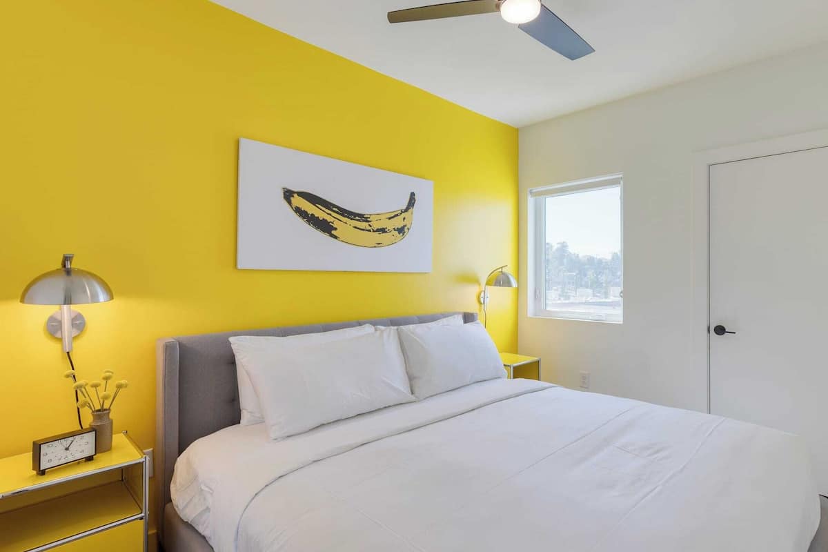 A bedroom with a bed, a ceiling fan, a window, and a door.