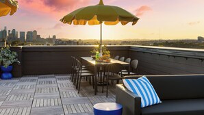 A rooftop terrace with a dining table, chairs, a sofa, and an umbrella. - The Carter by AvantStay (Nashville)