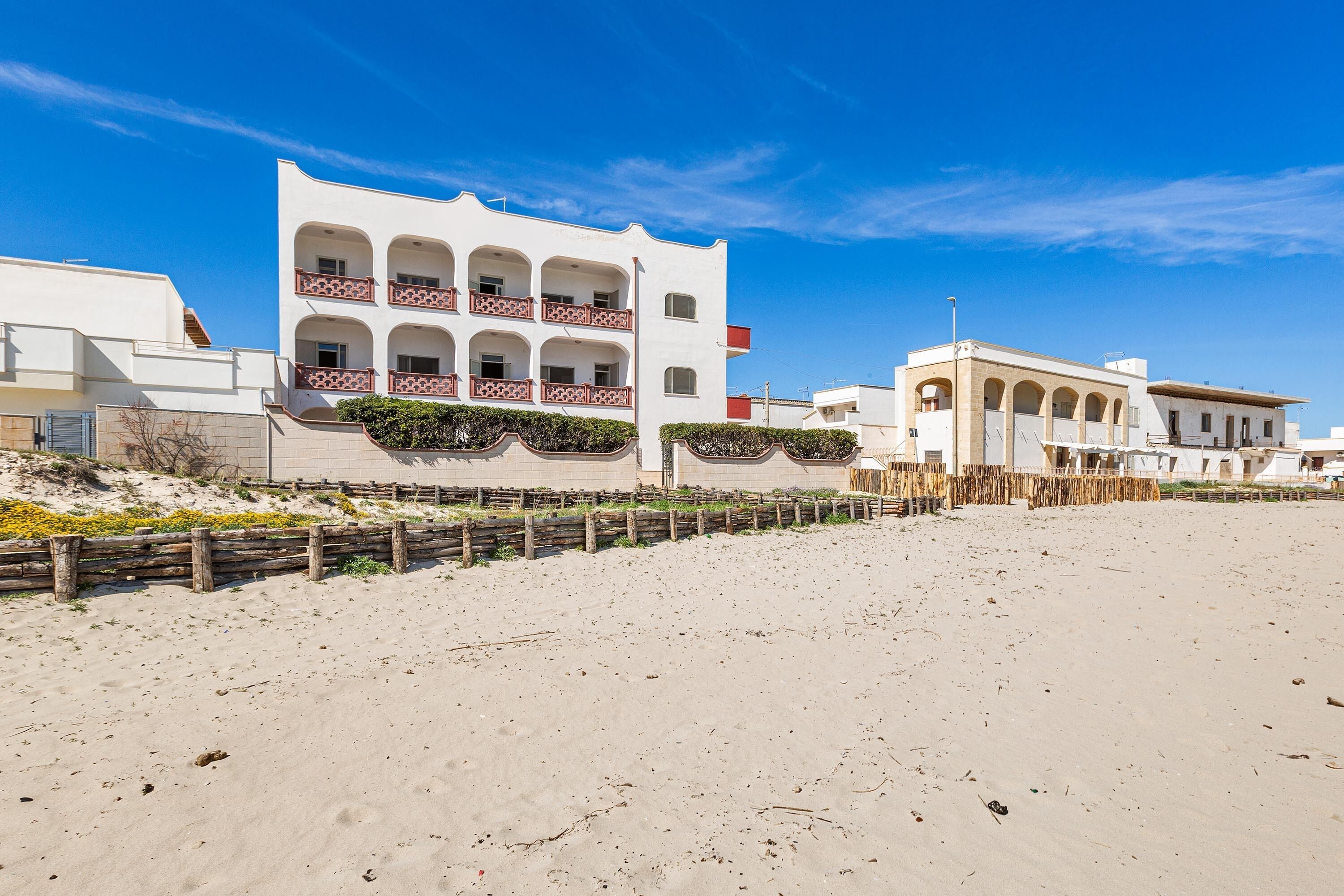 A beachfront building with multiple balconies and a sandy beach in the foreground.