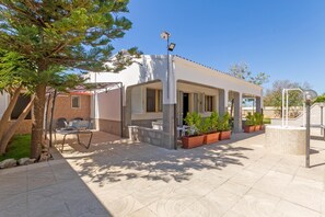 Um espaço ao ar livre coberto com terraço, assentos e plantas em vasos.