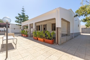 A modern building with a flat roof, large windows, and a covered patio area with potted plants. - 2903 Residence Mareluna - Bilo 1 by Barbarhouse (Porto Cesareo)