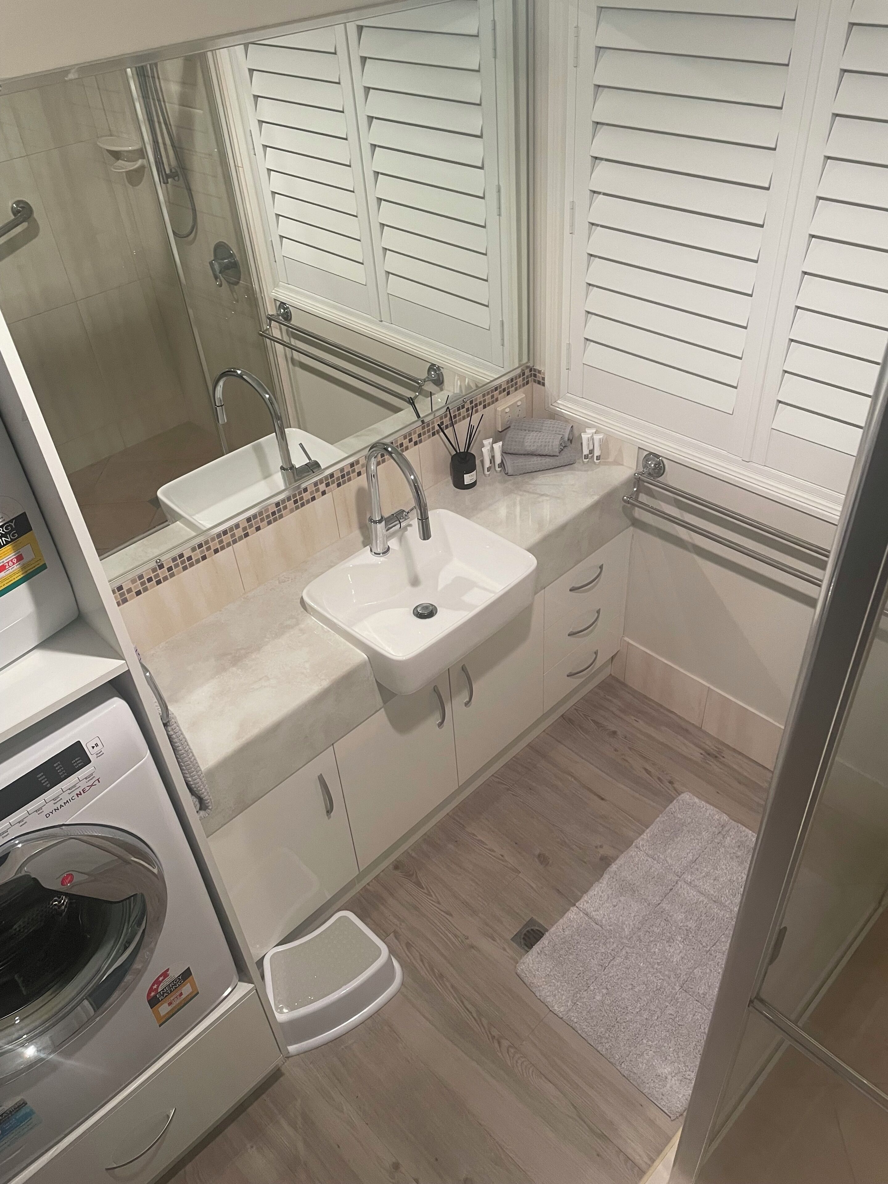 A bathroom with a sink, mirror, and a washing machine.