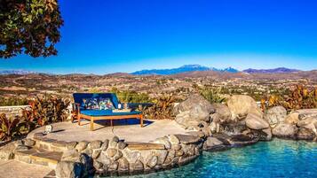 A pool area with a blue lounge chair and a view of distant mountains.