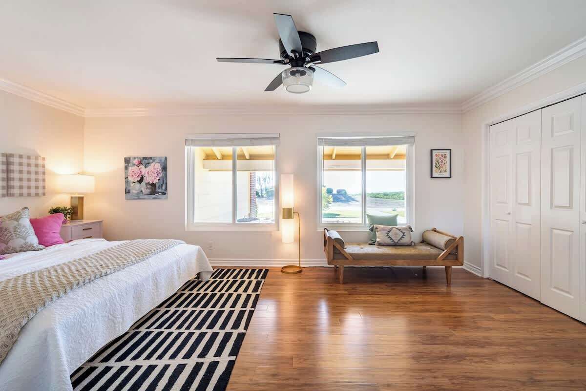 Un dormitorio con cama, mesita de noche, lámpara y ventana con vistas.
