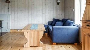 A room with a wooden floor, a wooden table with a blue cloth, a blue sofa with cushions, and a wooden cabinet. - 2 bedroom gorgeous home in Eggedal (Eggedal)