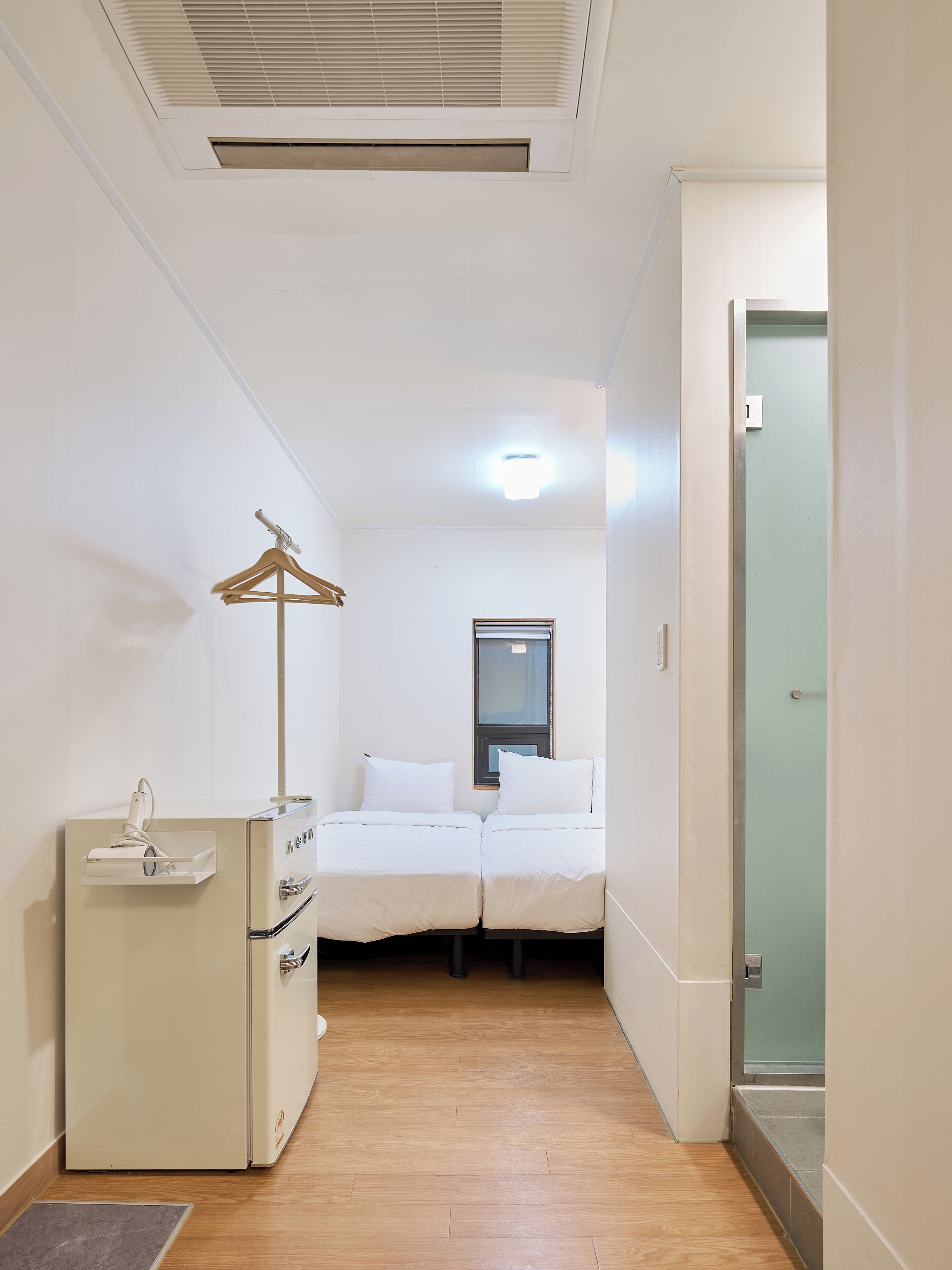 A small, clean room with a bed, a dresser, and a window.
