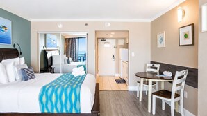 Een hotelkamer met een bed, een bureau, een stoel, een bijzettafeltje en uitzicht op een balkon.