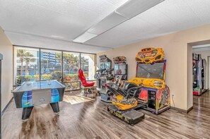 A room with a foosball table, arcade games, and a red chair. - Caravelle 619 (Myrtle Beach)