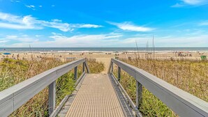 A wooden boardwalk leading to a beach with a clear sky. - Ocean Reef 303 (Myrtle Beach)