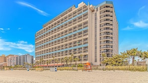 A multi-story hotel with balconies, located near a beach with palm trees. - Ocean Reef 303 (Myrtle Beach)