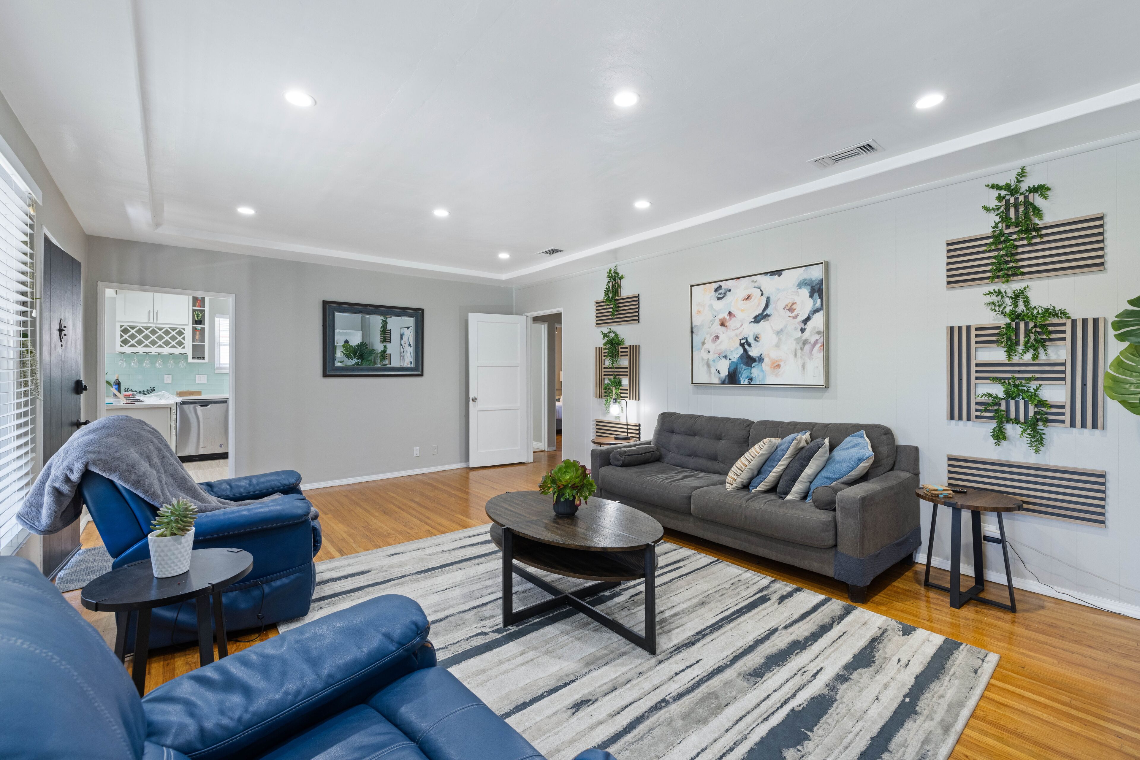 A modern living room with a grey sofa, blue armchairs, a coffee table, and a rug.