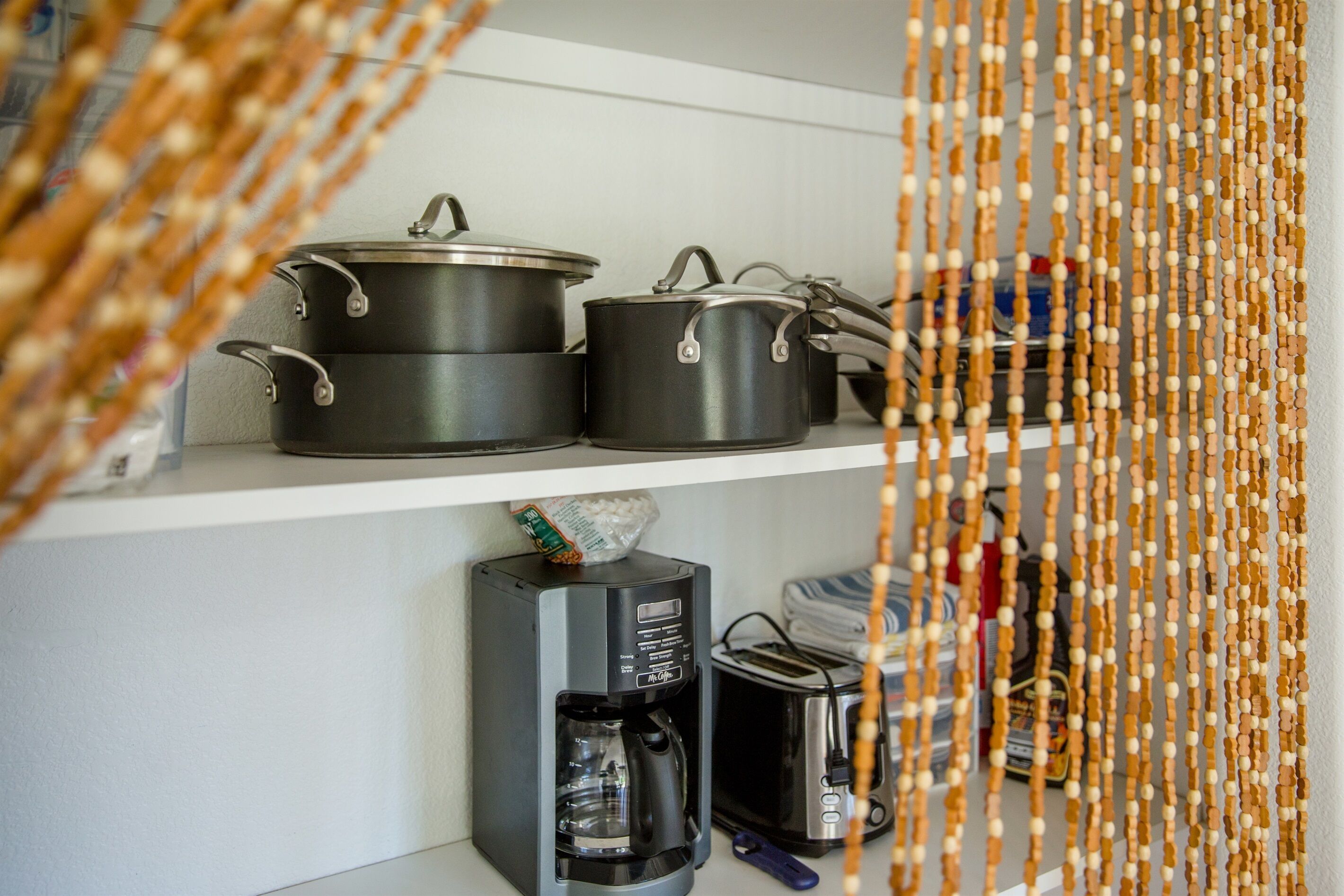 Una repisa en la cocina con ollas, una cafetera y un tostador.