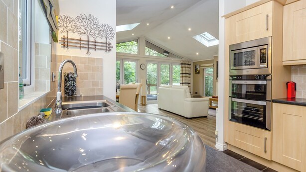 Een moderne keuken met een ruime roestvrijstalen jacuzzi, een inbouwoven en een eethoek met uitzicht op de omgeving.