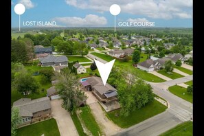 Vogelperspektive eines Wohngebiets mit Häusern, einem Golfplatz und einer markierten Position mit der Bezeichnung 'Lost Island'.