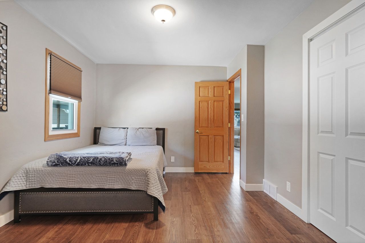 A bedroom with a bed, a window with blinds, a door, and a ceiling light.