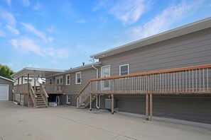 A two-story residential building with a covered outdoor area and a wooden deck.