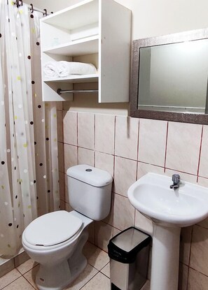 Un baño con inodoro, lavamanos y espejo sobre él.