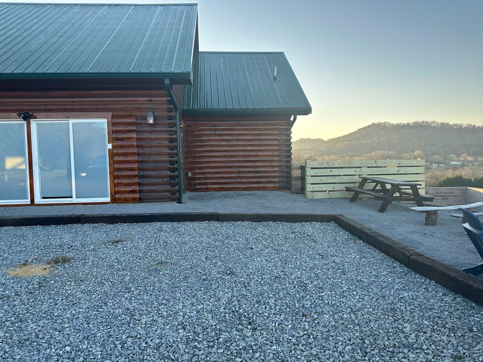 A rustic cabin with a gravel patio and a picnic table.