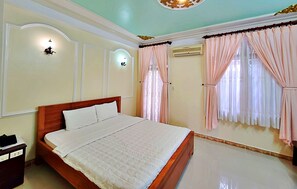 A bedroom with a wooden bed, white bedding, a nightstand, a wall-mounted light, and a window with curtains. - HANZ Hai Nam Hotel (Ho Chi Minh City)