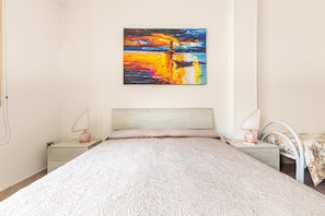 Un dormitorio con una cama, dos mesitas de noche y un cuadro colgado en la pared.