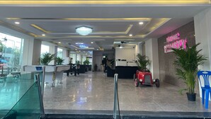 Eine Hotelhalle mit einer Rezeption, einer Sitzecke und einem Neonzeichen.