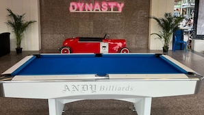 Ein Billardtisch mit einem Neonzeichen, das im Hintergrund 'PATONG DYNASTY' zeigt.
