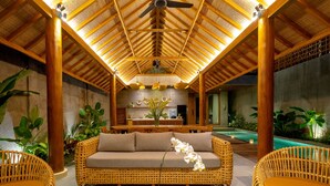 A cozy indoor seating area with a woven sofa, wicker chairs, and a dining table. - Jiwoku Villas (Canggu)