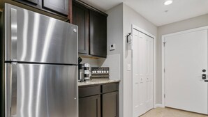 A kitchen with a stainless steel refrigerator, dark cabinets, a coffee maker, and a white door. - Queen Studio | Full Kitchen, Screened Balcony | 1 Small Dog | Ravines (Middleburg)
