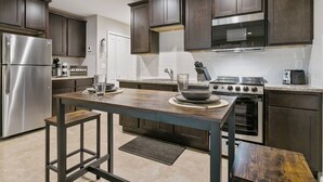A modern kitchen with dark wood cabinets, stainless steel appliances, and a central island with seating. - Queen Studio | Full Kitchen, Screened Balcony | 1 Small Dog | Ravines (Middleburg)